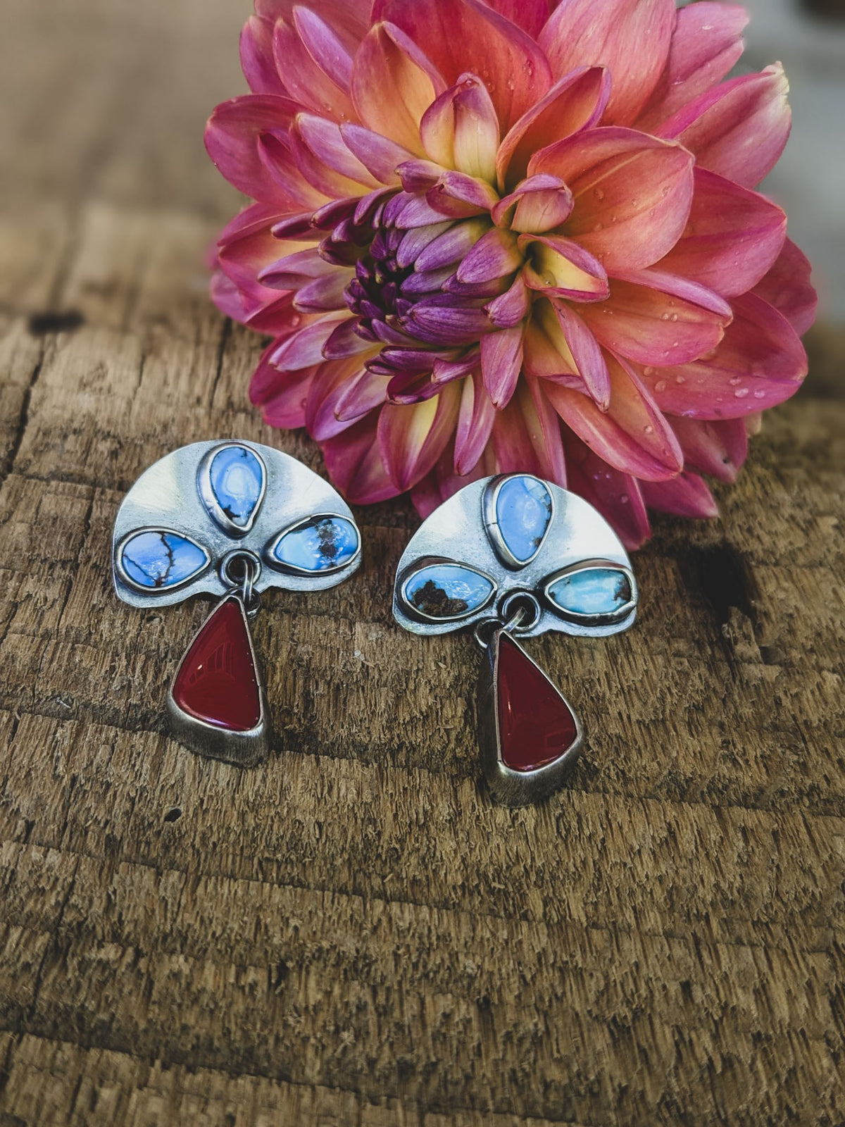 turquoise stones are set in sterling silver above dangles made of deep red carnelian