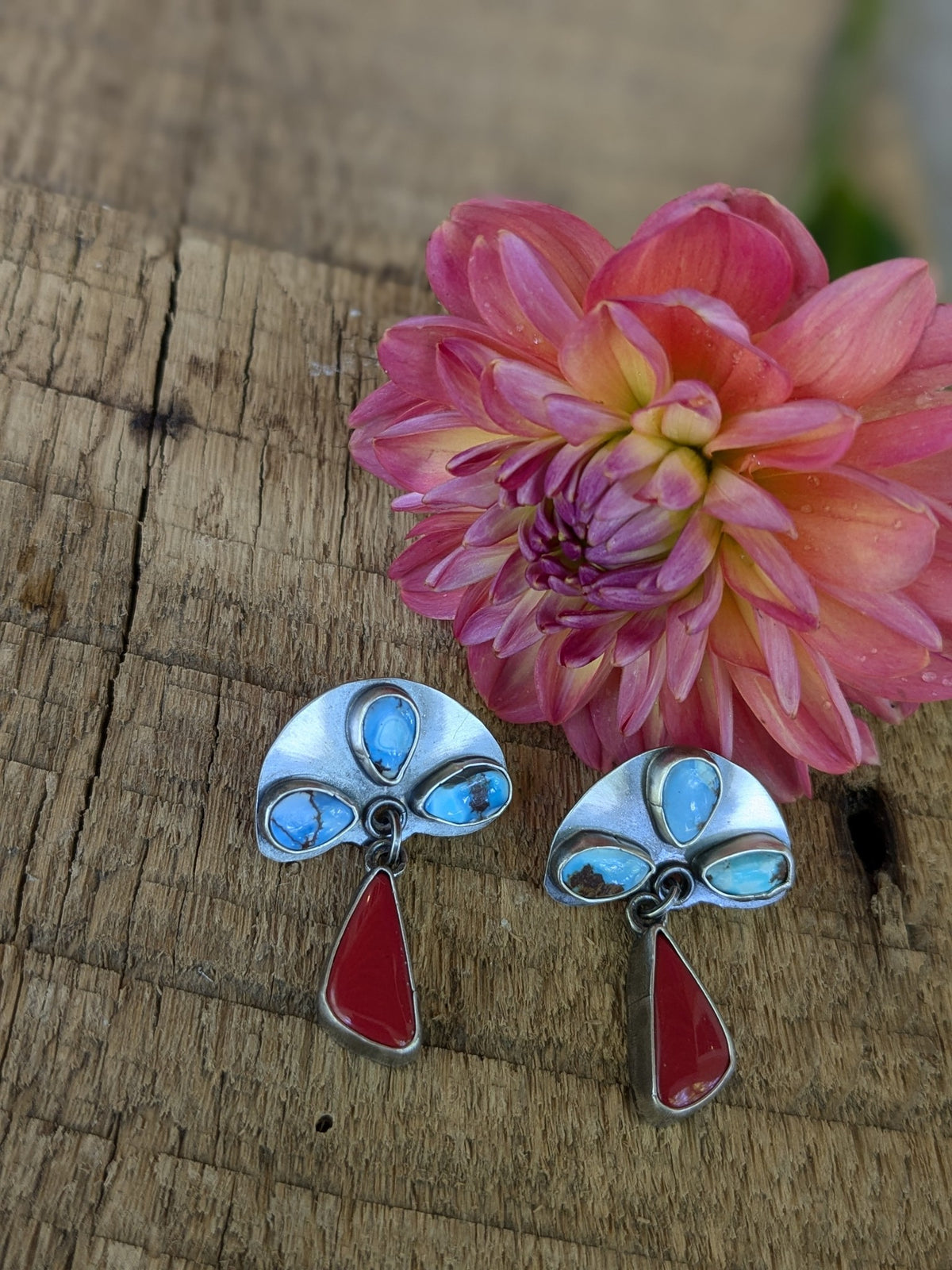 turquoise stones are set in sterling silver above dangles made of deep red carnelian